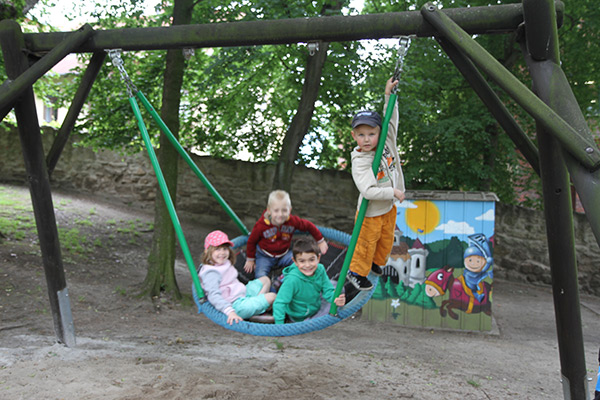 Vier Kinder in einer Nestschaukel